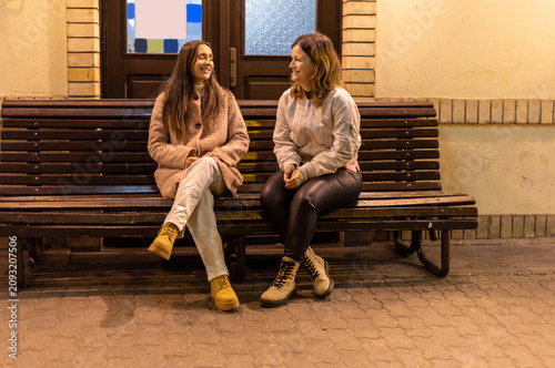 Women sitting on a bench at the train station waiting for the train