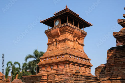 The iconic Menara Kudus mosque tower made of red bricks under a clear blue sky, a historic heritage site blending hindu and islamic architecture in Kudus, Central Java, Indonesia.