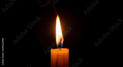 Single burning candle in darkness.