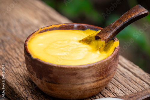 Ghee or clarified butter in wooden bowl, cooking oil, pure ghee on wooden background