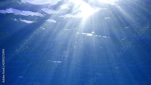 Ocean blue underwater with sunrays, Underwater Sea Deep Water Abstract Sunshine, sea wave , clean waters in summer time, Natural underwater seascape, sand on ocean floor and water surface sunlight.