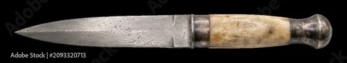 Obraz  z motywem Damascus steel hunting knife resting on  displaying unique metallurgical patterns and bone grip, traditional craftsmanship modern technology business concept