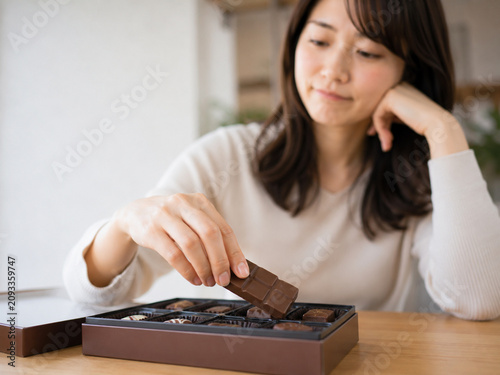 Young Woman Thoughtfully Choosing Chocolate from a Box