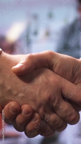 Close up of two business partners shaking hands confirming deal or agreement indoor