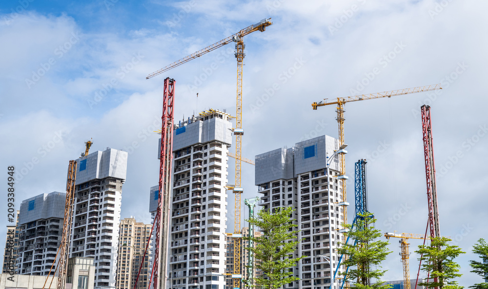 Fototapeta premium Real estate developments under construction and tower cranes at construction sites