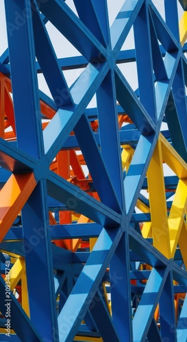 A detailed architectural view of a repeating geometric steel framework featuring interconnected triangular shapes under bright natural light, construction, structural, complex