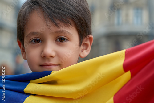 Boy holds Romanian flag during outdoor gathering
