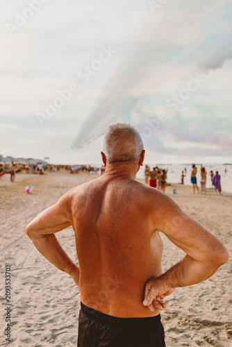Sunlit man watching Frecce Tricolori from sandy beach in Igea Marina Italy