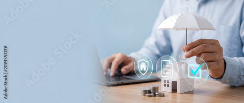 Real estate insurance concept showing miniature house model protected by white umbrella with home security icons overlay