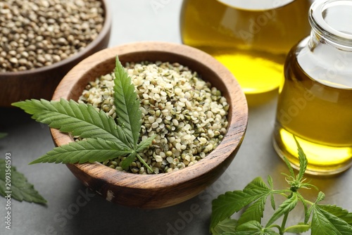 Cuadro en lienzo Hemp oil, seeds and leaves on grey table, closeup