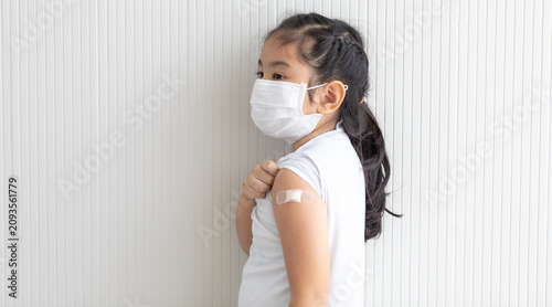 Foto Asian cute girl wearing face mask showing vaccinated arm