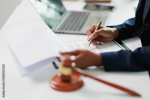 Lawyer reviewing legal documents and signing a contract at a desk, with a gavel nearby, representing justice, legislation, and resolving important business matters