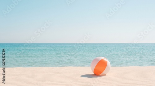Minimalist beach ball on sandy shore, orange and white inflatable toy on tropical coast, serene summer vacation background with turquoise ocean water