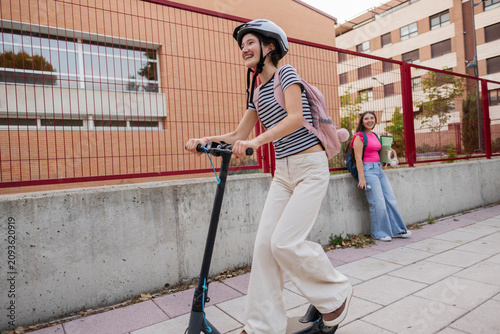 Young woman riding electric scooter laughing with friend