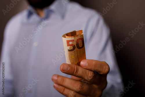 Hand holding a rolled fifty...