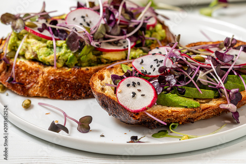 A close up of homemade avocado toast with various fresh toppings.