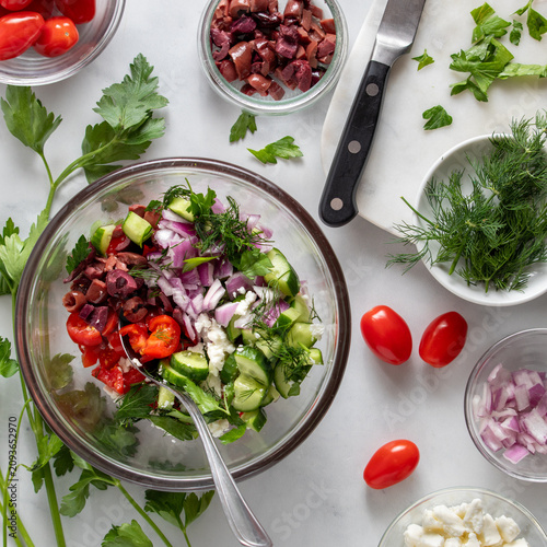 A bowl of fresh cut up vegetables to make a mediterranean salad.