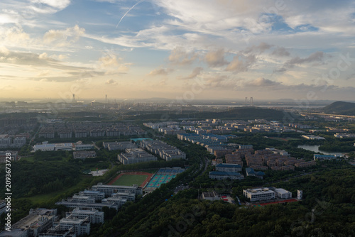 Принти на полотні Sunset aerial view of city outskirts beneath dramatic clouds