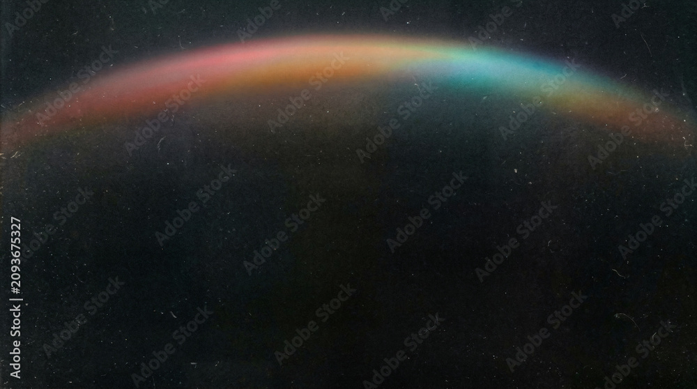 Obraz premium Dreamy rainbow arc in dark sky, subtle spectral light flare, atmospheric night background for weather and nature concepts