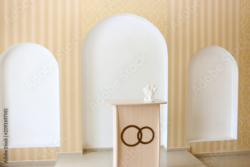 Foto Bright wedding ceremony area with a podium, decorative arches and angel figurine prepared for a marriage registration