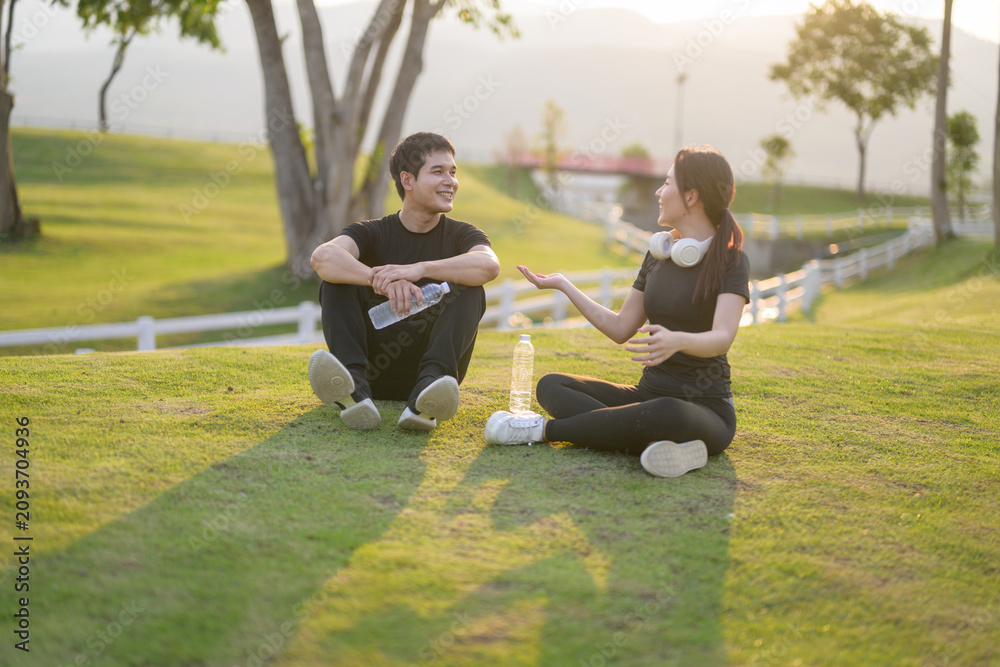 Fototapeta premium Young couple talking while relaxing on grass outdoors
