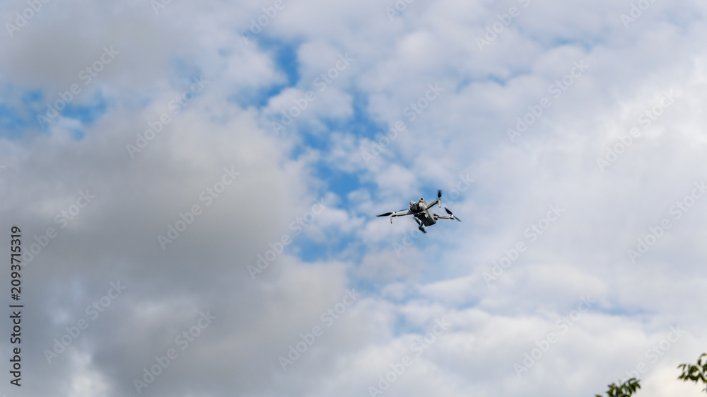Obraz premium Small drone flying in the sky with clouds and blue sky background