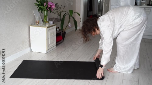 Static Shot Of Woman Unrolling Yoga Mat And Preparing For Home Workout In Bright Kitchen Living Room Apartment Interior.