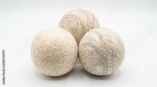 Three textured organic wool dryer balls arranged together against a clean and bright white background