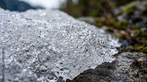 Close up macro texture of sparkling melting glacier ice crystals and cold water droplets on a rocky surface