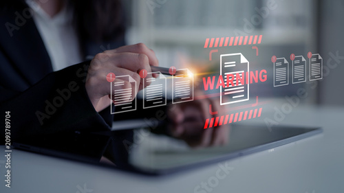 Fotografija A business professional reviews critical documents on a tablet, highlighting a warning alert to emphasize the importance of secure data management in a modern workspace
