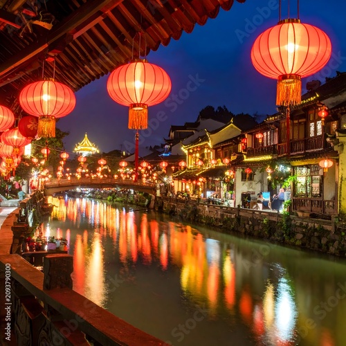 Vibrant nighttime cityscape with illuminated bridge and buildings.