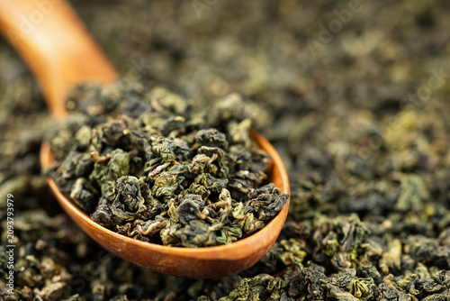 Premium dried oolong tea scoop on minimal solid background
