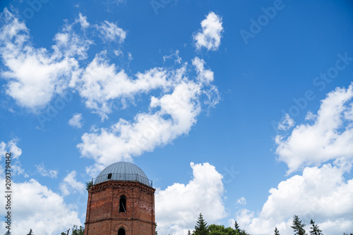 Fotografie Old brick tower with metal dome against blue sky