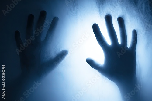 Two hands pressed against a glowing, misty, diffused light source