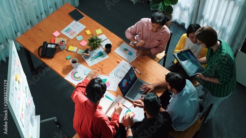 Top view of skilled business team discussing and talking about financial statistic to make decision for investment. Creative project manager looking at data analysis from laptop screen. Convocation.