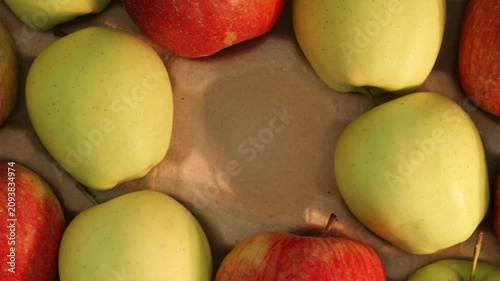 Man picking fresh red apple from center of wooden crate