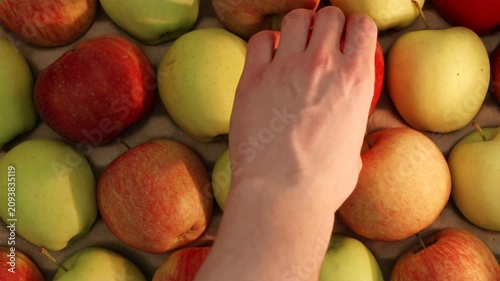Top down view of man hand picking red apple from basket