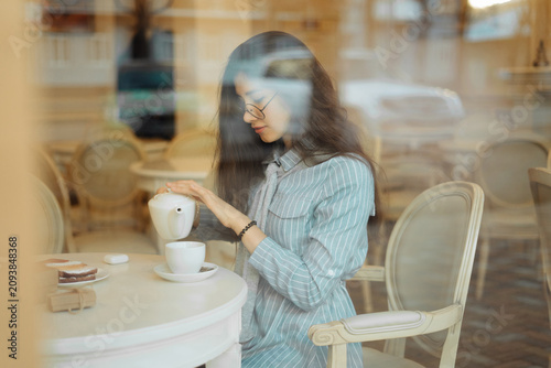 Slika na platnu beautiful asian girl enjoying an hot tea in cafe, view through window glass