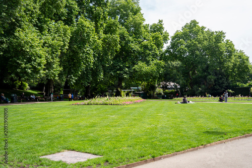 Fotografie People relaxing on the lawn of Victoria Embankment Gardens, a peaceful riverside park along the Thames between Charing Cross and Blackfriars stations, City of Westminster, London, UK