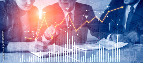 Photos A collaborative business team working together in an office space, focused on analyzing financial graphs and trends to inform strategic decisions and drive growth