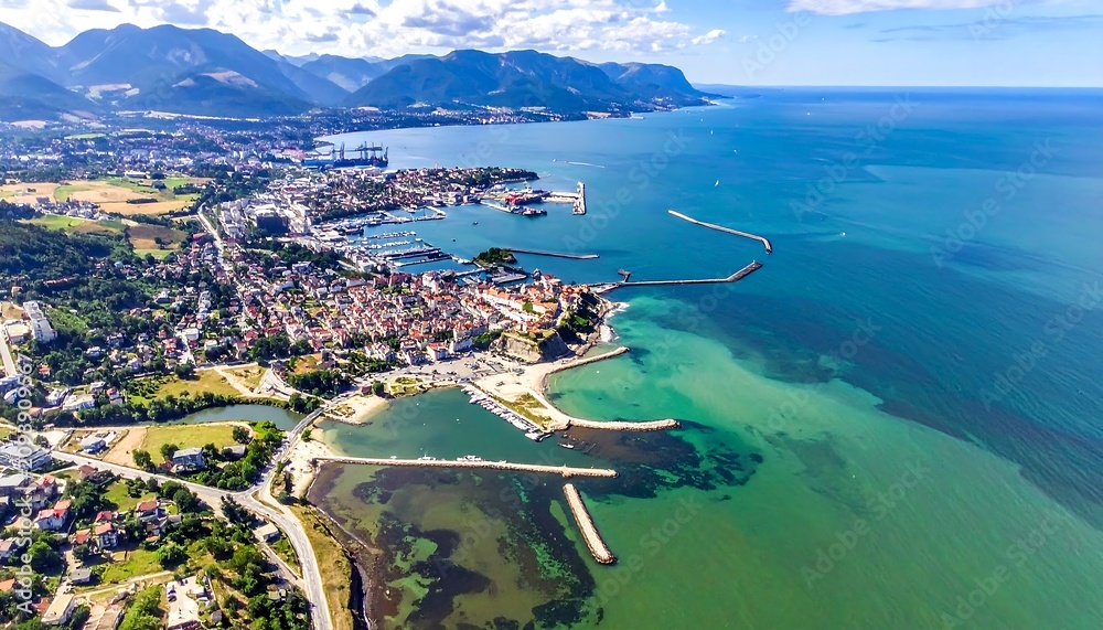Obraz premium Aerial view of a coastal town with a harbor and mountains