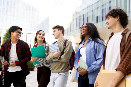 Happy students walking and talking on university campus