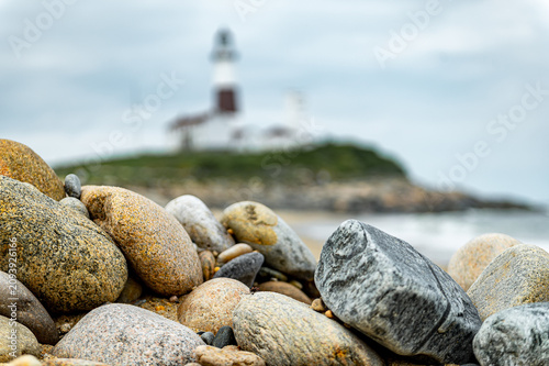 Foto Beach stones with blurred Montauk Point Lighthouse background