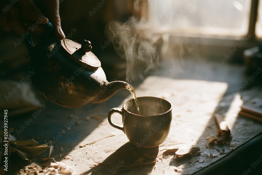 Fototapeta premium Clay teapot pouring stream of tea on rustic workshop table