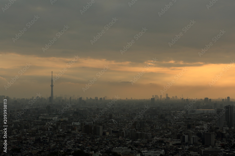 Fototapeta premium 雨雲の隙間から差し込む夕陽と天使の梯子 都市風景 / Sunbeams and Crepuscular Rays Shining Through Rain Clouds City Landscapes