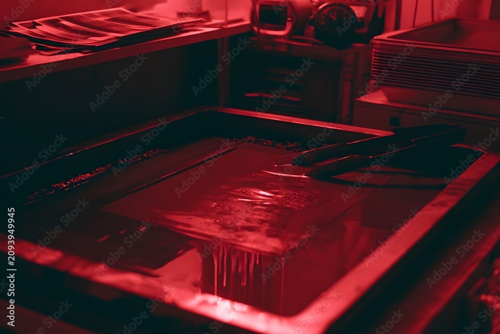 Fototapeta premium Wet photo print dripping in developer tray under red light