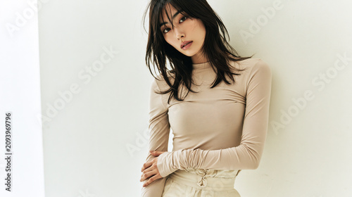 beautiful young woman in minimalist white studio with soft korean fashion editorial style