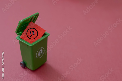 Environmental crisis and pollution sadness concept with unhappy icon in miniature recycling bin