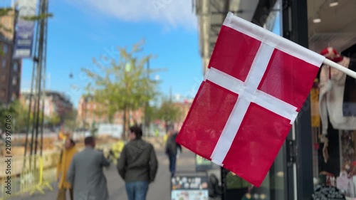 Close up of Danish flag waving outside shop on Copenhagen city street, Denmark