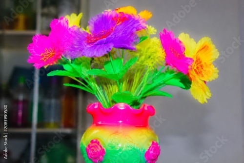 A cheap plastic flower in a garish vase, tacky aesthetic with bright colors.